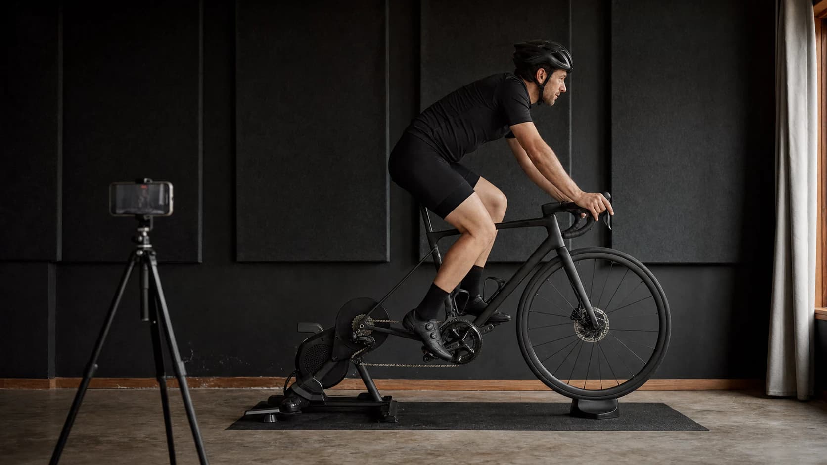 A side view of a cyclist riding on an indoor bike stand.